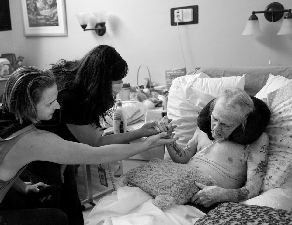 Death doula Kimberly Peterson gently replaces her hand with Sylys Dye’s hand as they keep vigil with Dye’s grandfather Paul Youngblood at The INN Between in Salt Lake City on Sunday, Aug. 6, 2023. Youngblood died five days later. | Laura Seitz, Deseret News