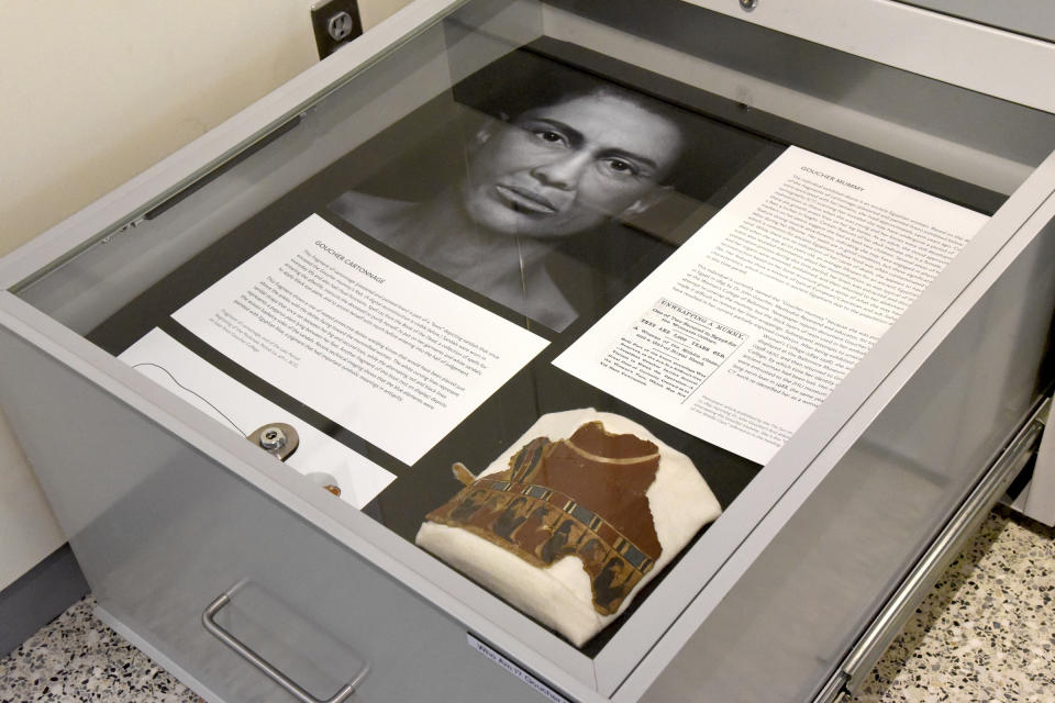 In a Sept. 26, 2018 photo, a pull-out drawers offer more information about the facial depiction process at the new Johns Hopkins Archaeological Museum exhibit, "Who Am I? Remembering the Dead Through Facial Reconstruction," in Baltimore. Pictured here is the facial depiction of the Goucher mummy, and her "boot." FaceLab, Liverpool John Moores University, worked with Hopkins to create facial depictions of the Goucher mummy, ca. 4th c. BCE, and the Cohen mummy, ca. 664 - 525 BCE. (Amy Davis/The Baltimore Sun via AP)