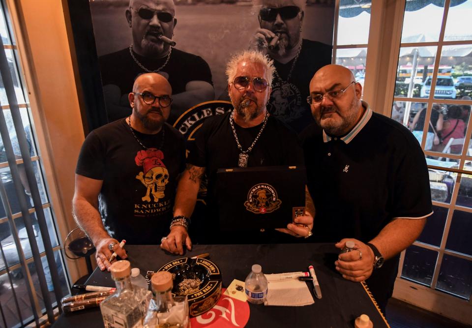 Erik Espinosa, Guy Fieri and Smoke Inn proprietor Abe Dababneh pose for a photo in Smoke Inn, Thursday, Sept. 21, 2023, in Port St. Lucie. Fieri along with Espinosa promoted the hand-crafted Knuckle Sandwich cigar line, signing autographs and taking photos with patrons who bought a box of the cigars.