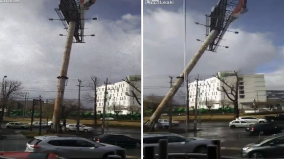 Strong winds pushed the huge billboard over, landing on top of two cars. Photo: LiveLeak