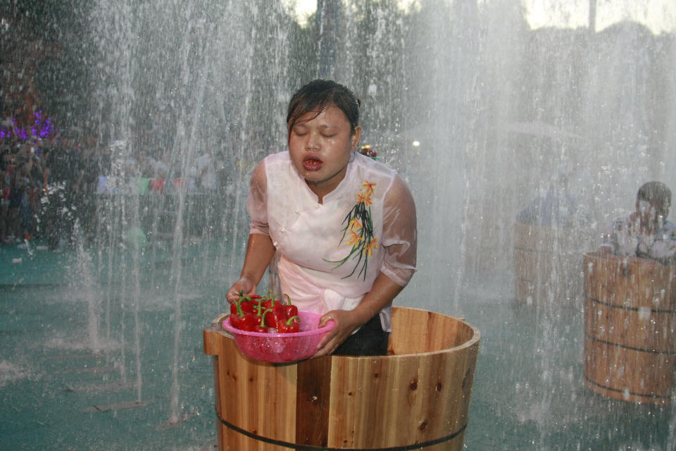 Tourists standing in the ice buckets eat peppers in the fountain during a competition at Song Dynasty Town on July 20, 2016 in Hangzhou, Zhejiang Province of China.