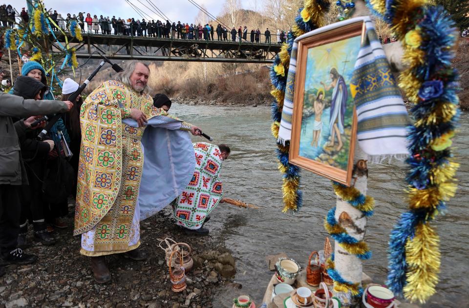 Priests bless water in a river as locals celebrate Epiphany in Kryvorivnya village in the Carpathian Mountains near Ivano-Frankivsk, western Ukraine, 6 January 2023 (EPA)