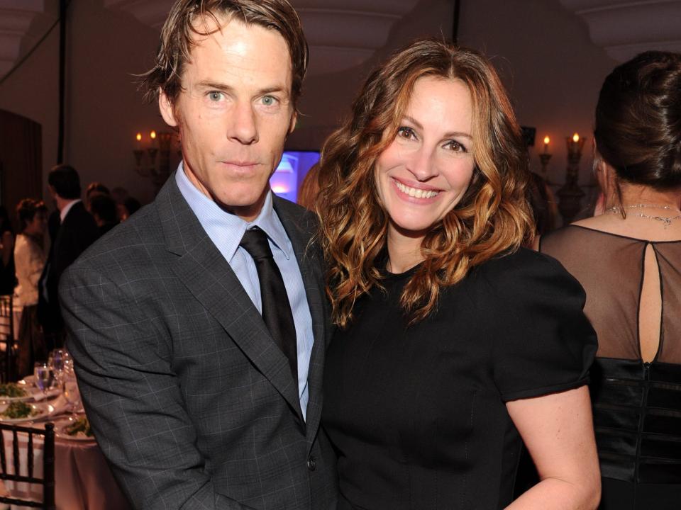 Danny Moder, in a gray suit and blue shirt, poses with his arms around a smiling Julia Roberts' waist in this photo from 2014.