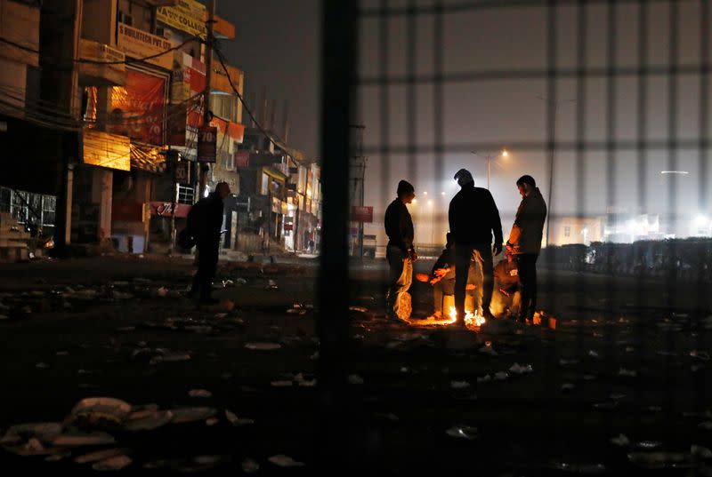 Local residents stand next to a bonfire as they block a road during a protest against a new citizenship law, in New Delhi