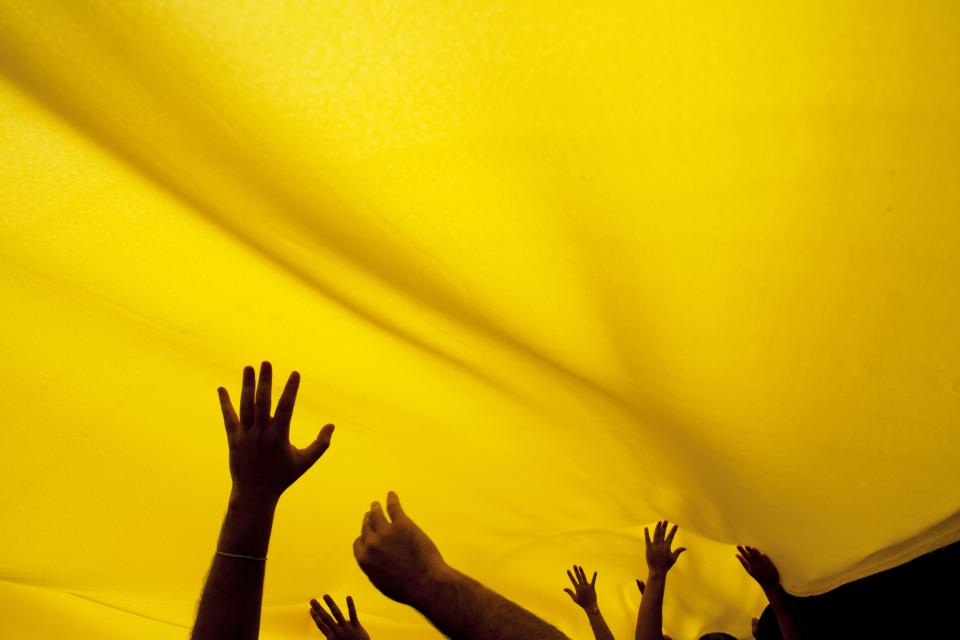 Demonstrators raise their hands under a Venezuelan flag as they march in Caracas, Venezuela, Sunday, March 2, 2014. Since mid-February, anti-government activists have been protesting high inflation, shortages of food stuffs and medicine, and violent crime in a nation with the world's largest proven oil reserves. (AP Photo/Rodrigo Abd)