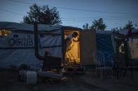 In this Thursday Oct. 3, 2019 photo, an Afghan man looks out of his tent in a makeshift refugee and migrant camp on the fringes of the overcrowded Moria camp on the Greek island of Lesbos. Greece's conservative government announced Wednesday Nov. 20, 2019, plans to overhaul the country's migration management system, and replacing existing camps on the islands with detention facilities and moving and 20,000 asylum seekers to the mainland over the next few weeks. (AP Photo/Petros Giannakouris)