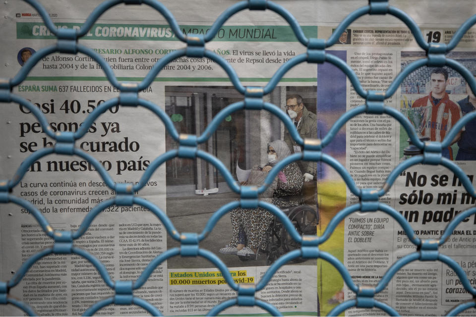 Newspapers are seen covering a window behind a closed shutter of a bar as the lockdown to combat the spread of coronavirus continues in Madrid, Spain, Friday, April 10, 2020. Spain's parliament has endorsed a government request to extend by two more weeks the current state of emergency. Strict rules that keep people at home except for shopping for food and medicine and the shutting down of all non-essential industry have helped Spain reduce its daily rate of contagion growth. The COVID-19 coronavirus causes mild or moderate symptoms for most people, but for some, especially older adults and people with existing health problems, it can cause more severe illness or death. (AP Photo/Paul White)