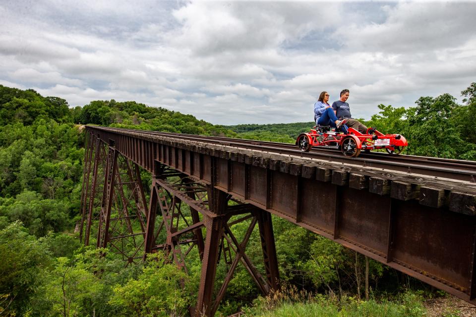 Mary Joy Lu, CEO of Rail Explorers and her husband Alex Catchpoole, Rail Explorers COO, ride over the 156-foot-tall Bass Point Creek High Bridge outside of Boone, Wednesday, July 6, 2022.