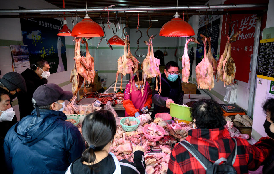 People wearing protective face masks shop at a chicken stall at a wet market in Shanghai on Feb. 13, 2020. (Noel Celis / AFP via Getty Images)