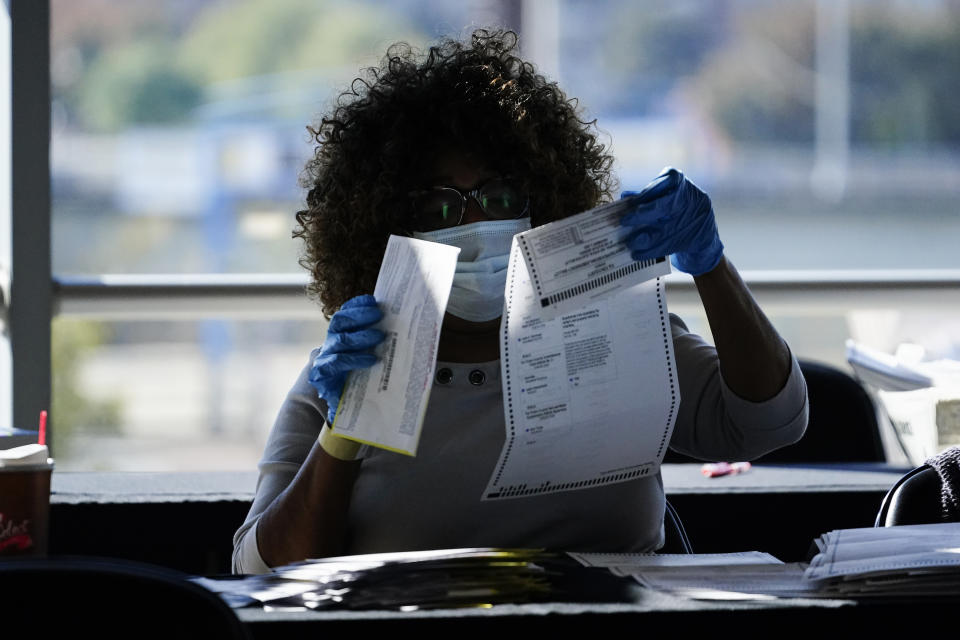 An election personnel examines a ballot as vote counting in the general election continues at State Farm Arena, Wednesday, Nov. 4, 2020, in Atlanta. (AP Photo/Brynn Anderson)