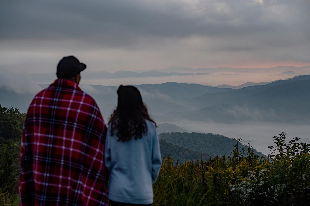 Arnold Gutierrez, left, and Angela Foster take in the view from the Pounding Mill Overlook along the Blue Ridge Parkway as the sun rises on October 5, 2023.