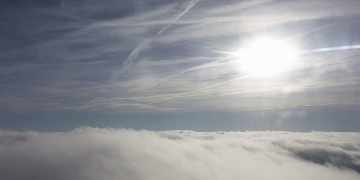 blanket of clouds in the bottom half of the image, with the sun in the top right hand corner