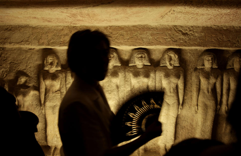 FILE - In this Thursday, Oct. 11, 2012 file photo, a tourist uses a hand fan, inside the tomb that belongs to Queen Meresankh III at the historical site of the Giza Pyramids, near Cairo, Egypt. he past month saw a drop in tourists to Egypt, scared off by scenes of protests and clashes over the constitution, in new pain to a crucial industry gutted the past two years by turmoil. Tourism workers worry things won’t get any better even now that the charter has been passed: Egypt’s power struggles threaten to erupt into more unrest at any time, and some fear Islamists will eventually try to rein in alcohol and beach tourism. (AP Photo/Nariman El-Mofty, File)