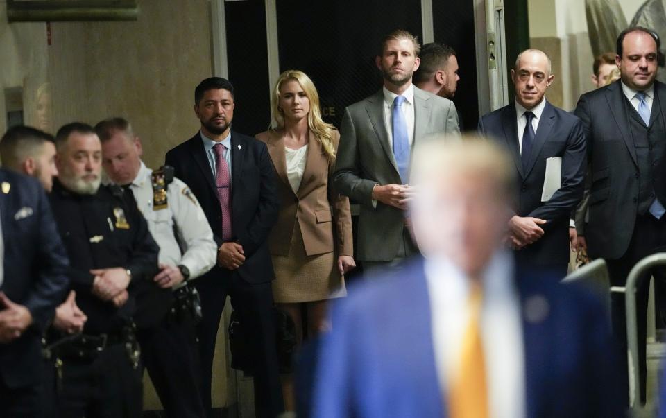 Donald Trump's entourage listen as he speaks to reporters during his arrival at his "hush money" trial