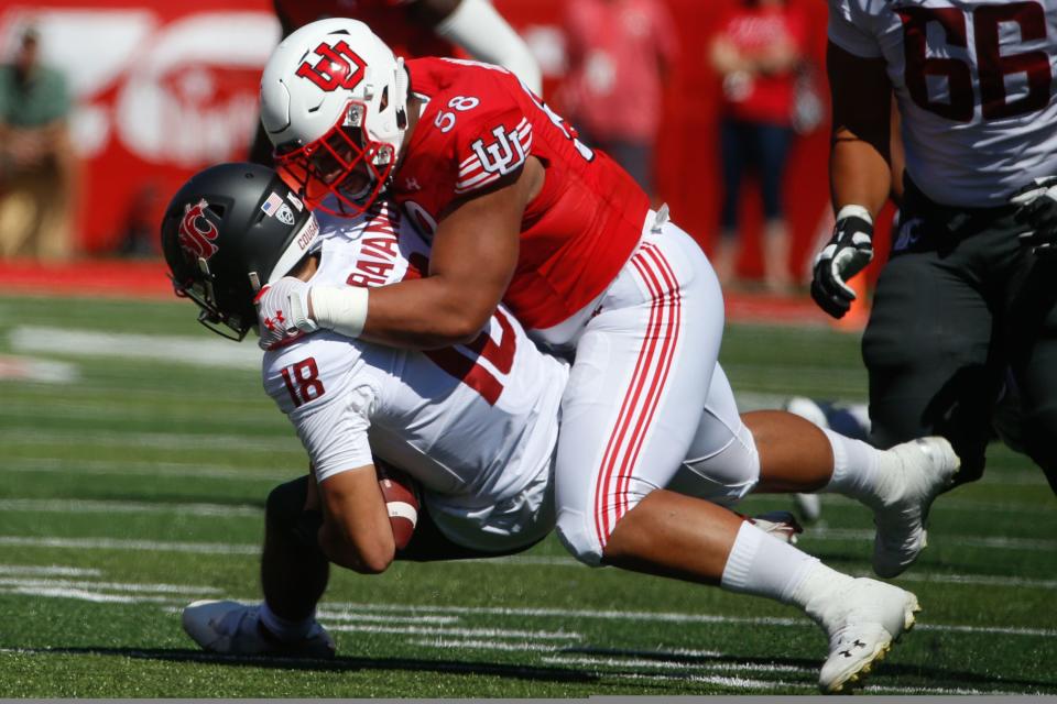 Utah defensive tackle Junior Tafuna. wearing a white helmet and red jersey, tackles Washington State quarterback Jarrett Guarantano