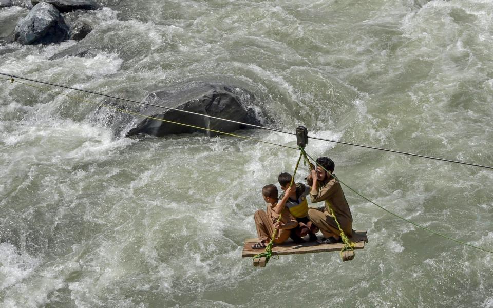 Local residents use a temporary cradle service to cross the river Swat after heavy rains in Bahrain town of Swat valley in Khyber Pakhtunkhwa province - ABDUL MAJEED/AFP via Getty Images