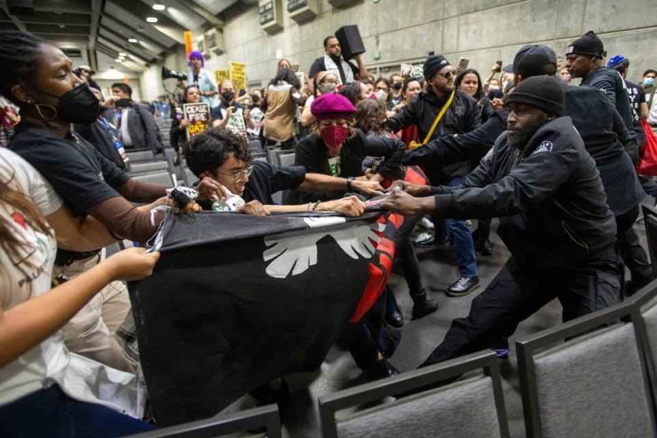 Demonstrators wrestle with security guards over a banner calling for a cease-fire in the Israel-Hamas war during a protest at the Democratic nominating convention at the SAFE Credit Union Convention Center in Sacramento on Saturday, Nov. 18, 2023.