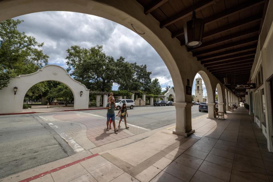 People cross a street between archways.