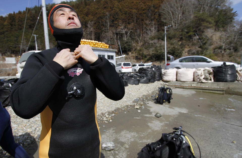 In this Sunday, March 9, 2014 photo, Yasuo Takamatsu wears a diving suit to take a diving lesson at Takenoura bay, Miyagi prefecture, northern Japan. Nearly three years after the earthquake and tsunami disaster that struck Japan's northern pacific coastline, Takamatsu is learning to scuba dive in hopes of finding his wife. As Japan marks the third anniversary of the 2011 tsunami Tuesday, 2,636 people remain missing, their bodies presumably swept out to sea. Another 15,884 have been confirmed dead. (AP Photo/Koji Ueda)