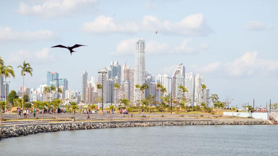 Landscape of skyscrapers in financial center of Panama and people walking along the promenade with sea birds flying