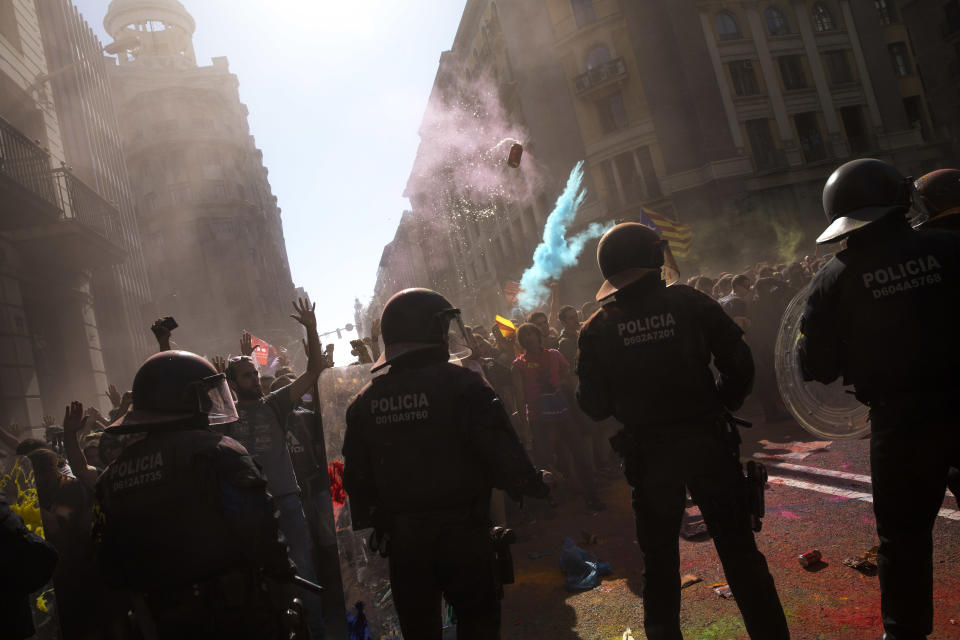 Demonstrators throw a can of beer and power painting at Catalan police officers during clashes with pro independence protesters on their way to meet demonstrations of members and supporters of National Police and Guardia Civil in Barcelona on Saturday, Sept. 29, 2018. (AP Photo/Emilio Morenatti)