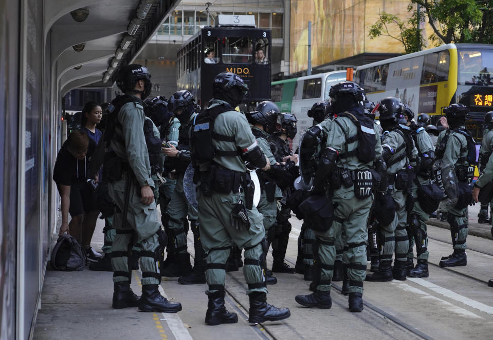 Police in full protective gear patrol gather near a streetcar stop in Hong Kong on Saturday, Oct. 5, 2019. All subway and train services were suspended, lines formed at the cash machines of shuttered banks, and shops were closed as Hong Kong dusted itself off and then started marching again Saturday after another night of rampaging violence decried as "a very dark day" by the territory's embattled leader. (AP Photo/Vincent Yu)