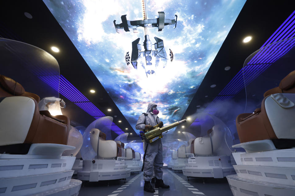 A volunteer with the Blue Sky Rescue team performs disinfecting of the virtual reality theater in a cinema before it reopens for business in Beijing Friday, July 24, 2020. Theaters in China, the world's second largest movie market, this week reopened from the coronavirus shut down with theaters limited to 30% capacity. (AP Photo/Ng Han Guan)