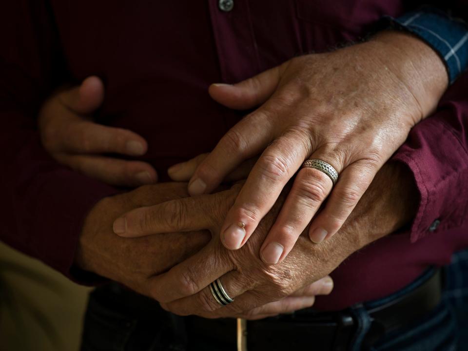 Two pair of hands holding one another with rings on both hands