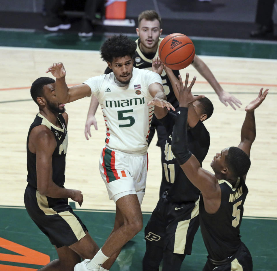 Miami guard Harlond Beverly (5) passes the ball around Purdue defenders during the first half of an NCAA college basketball game Tuesday, Dec. 8, 2020, in Coral Gables, Fla. (Al Diaz/Miami Herald via AP)