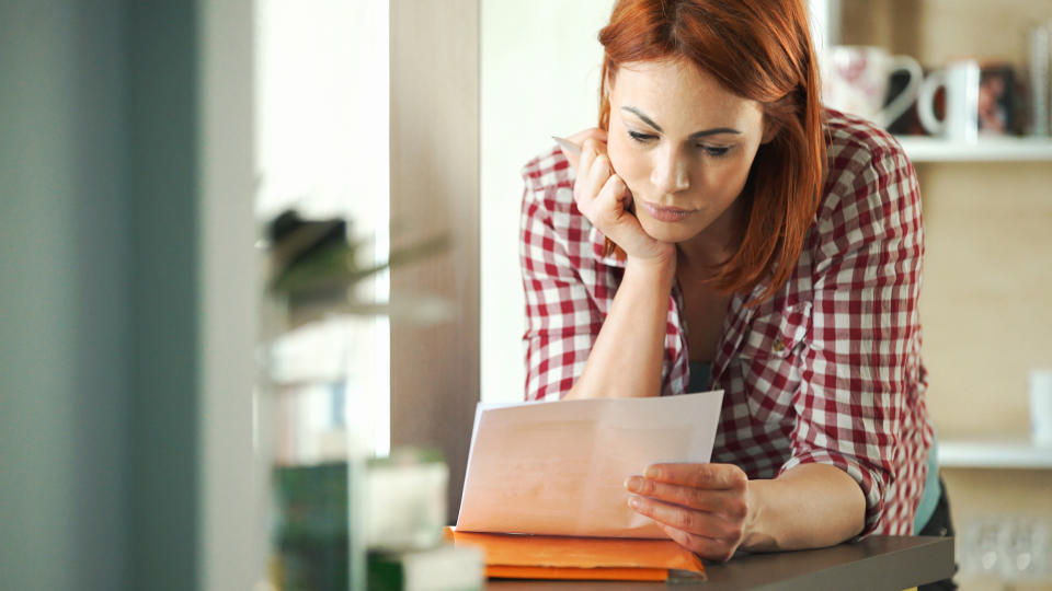 Closeup of attractive mid 30's housewife looking at monthly bills that seem to have skyrocketed.