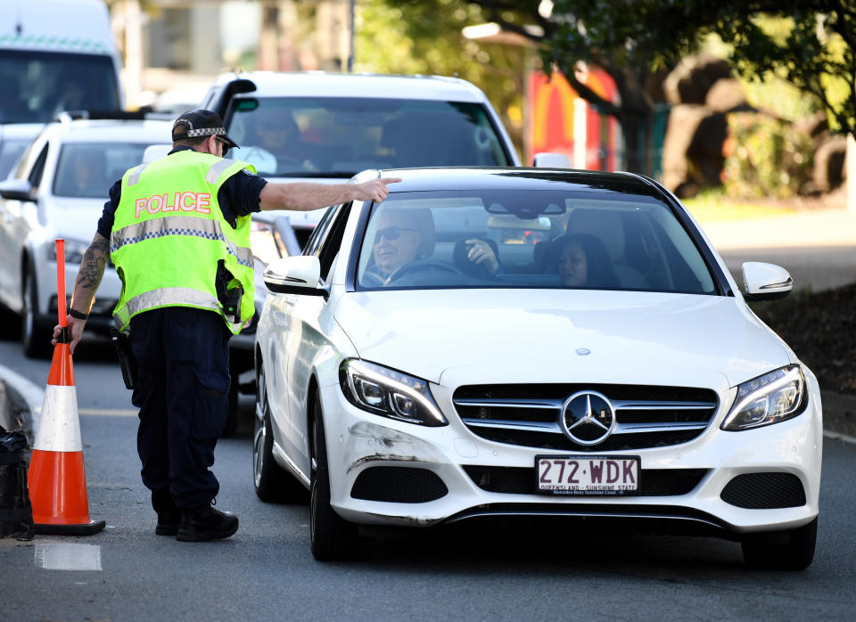 A police officer directs a car for further inspection at a check point on the Queensland-New South Wales border in Coolangatta on the Gold Coast.