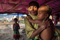 <p>Fleeing violence in Myanmar, Rohingya families arrive at Kutupalong. A Rohingya woman holds a young child in her makeshift tent at Kutupalong camp in Bangladesh on September 20, 2017. (Photograph by Paula Bronstein/UNHCR) </p>