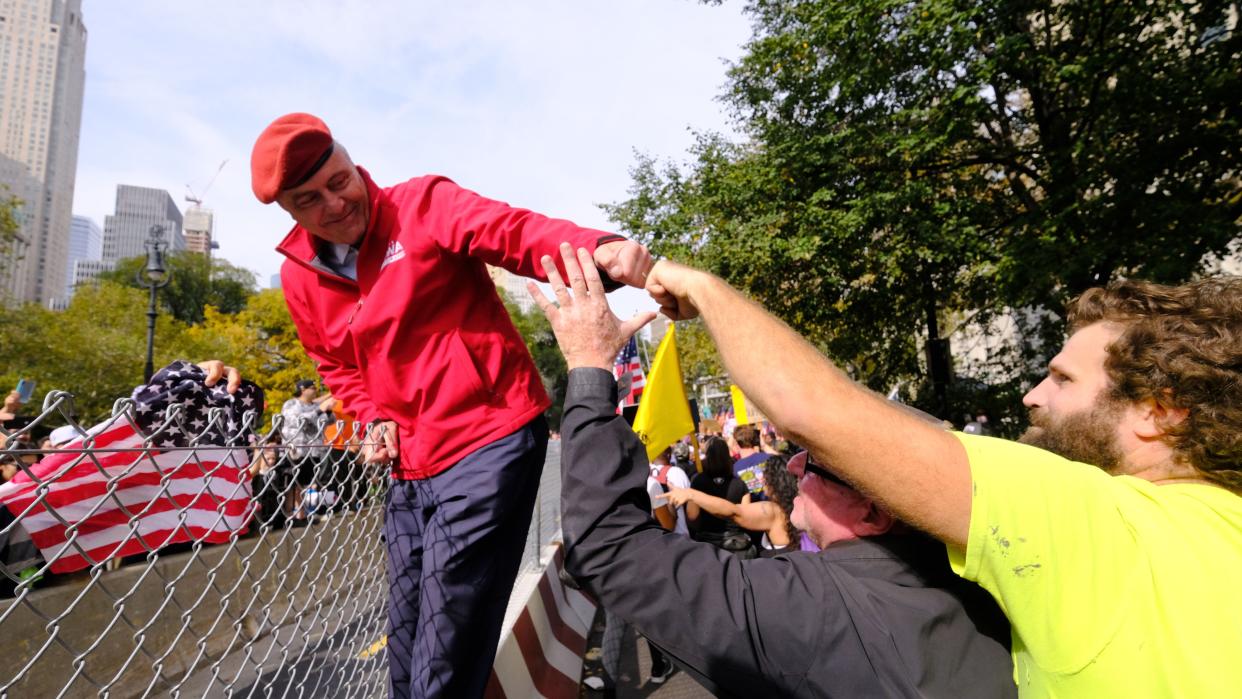 Republican New York City mayoral candidate Curtis Sliwa hanging on a fence to greet anti-vax protesters on the Brooklyn Bridge heading into lower Manhattan, New York on Monday, Oct. 25, 2021.