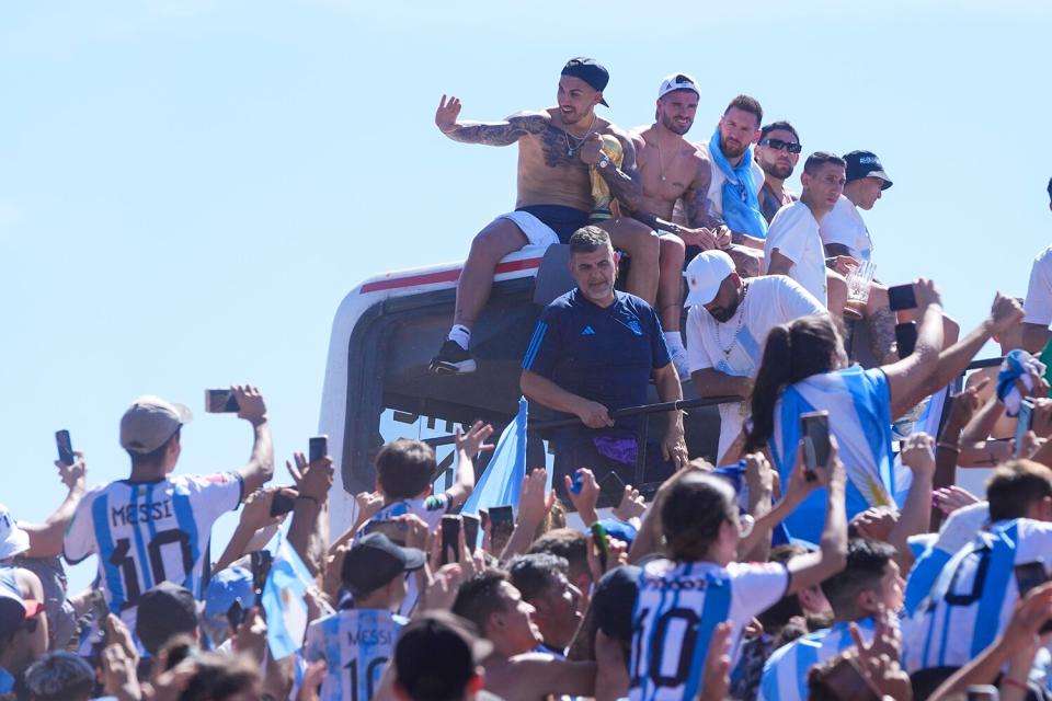 From left to right, Leandro Paredes, Rodrigo De Paul, Lionel Messi and Nicolas Otamendi sit on the top of a bus during a homecoming parade for the team that won the World Cup tournament in Buenos Aires, Argentina