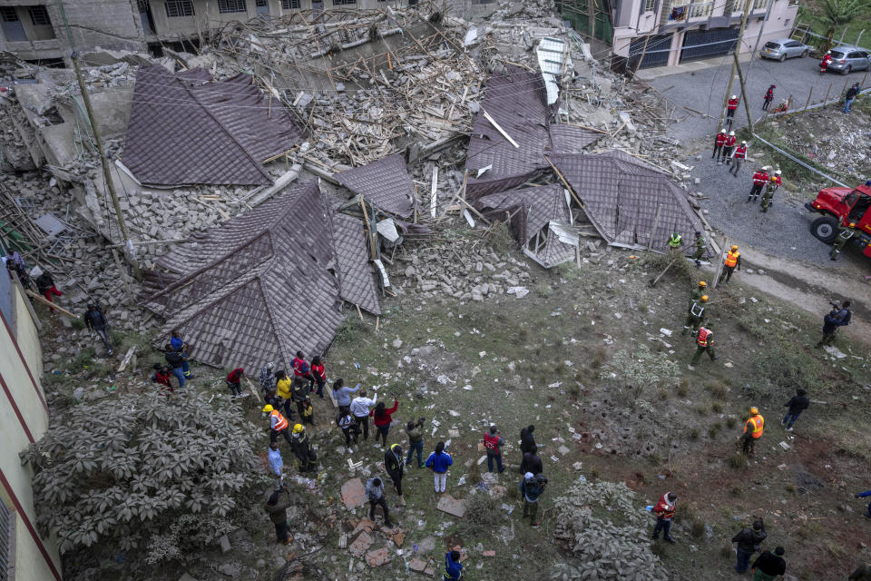 Rescue workers and media gather at the scene of a building collapse in the Kasarani neighborhood of Nairobi, Kenya Tuesday, Nov. 15, 2022. Workers at the multi-storey residential building that was under construction are feared trapped in the rubble and rescue operations have begun, but there was no immediate official word on any casualties. (AP Photo/Ben Curtis)