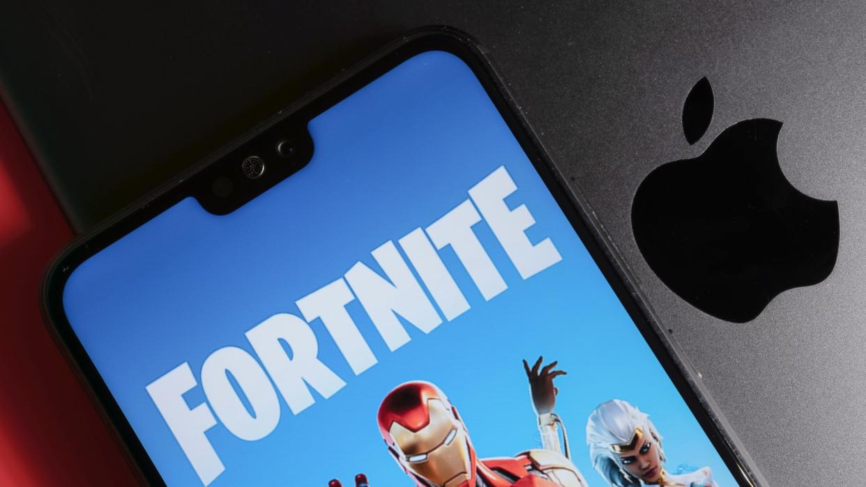  Fortnite running on phone on top of MacBook showing Apple logo. 