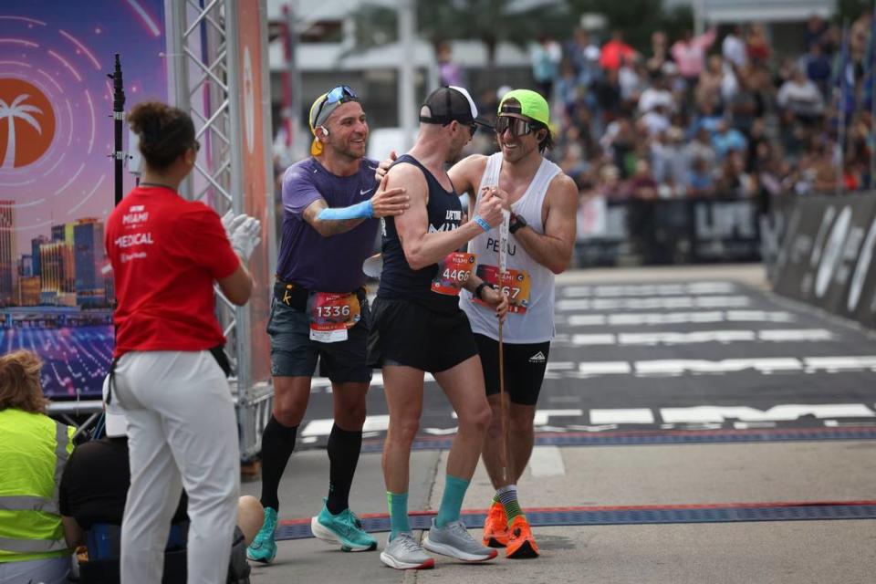 Three runners embrace after crossing the finish line during the Life Time Miami Marathon on Sunday, Jan. 29, 2023, in Miami.