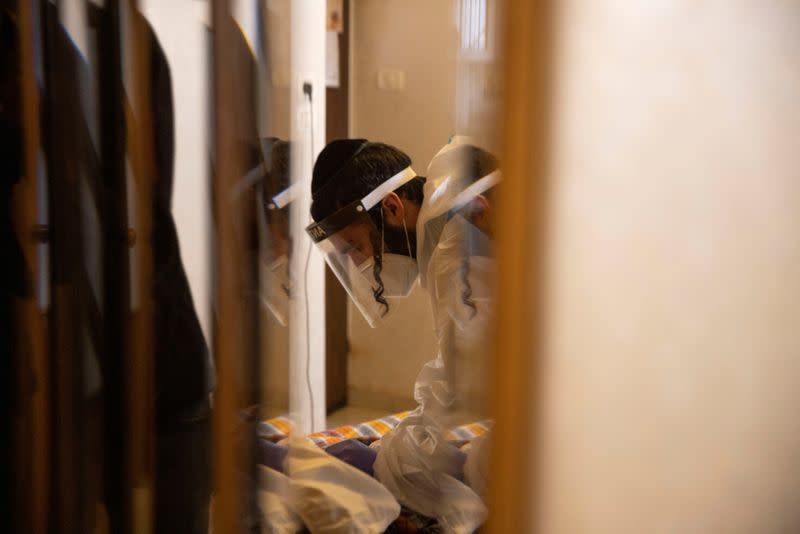 An ultra-Orthodox Jewish volunteer from Chasdei Amram, which provides home relief to people affected by the coronavirus disease (COVID-19), wears personal protective equipment (PPE) as he visits an elderly woman in Jerusalem