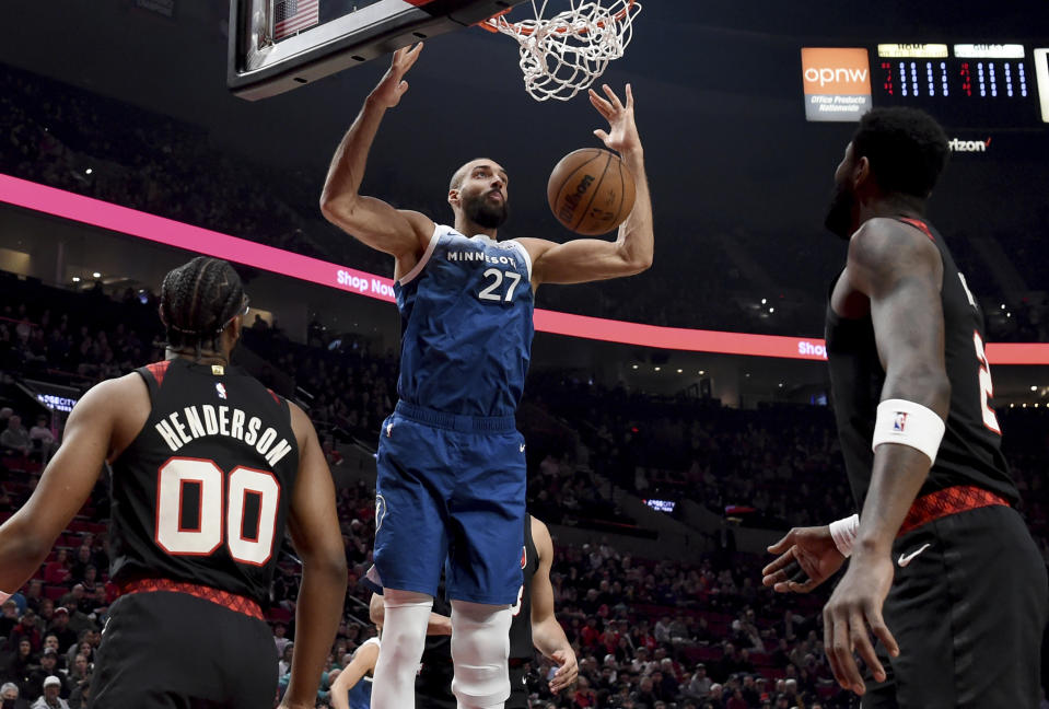 Minnesota Timberwolves center Rudy Gobert dunks as Portland Trail Blazers guard Scoot Henderson, left, and center Deandre Ayton, right, watch during the first half of an NBA basketball game in Portland, Ore., Thursday Feb. 15, 2024. (AP Photo/Steve Dykes)
