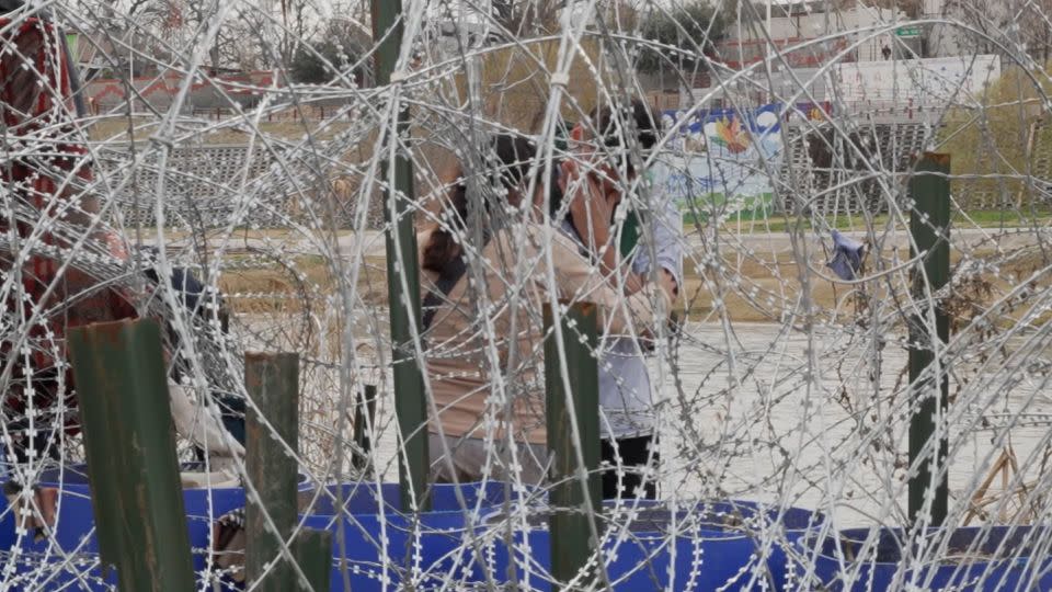Venezuelan couple Kevin and Vanessa stand behind razor wire at the US-Mexico border. - CNN