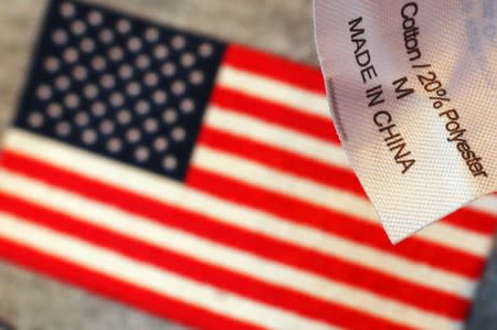 The label reading "Made in China" on a sweatshirt is seen over another shirt with a U.S. flag at a souvenir stand in Boston