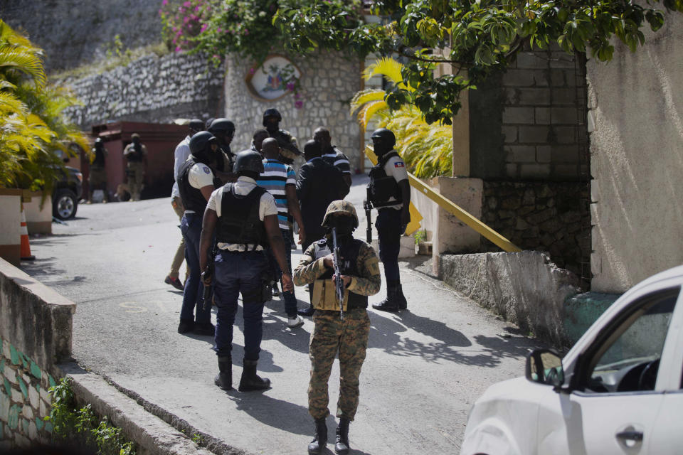 Security forces conduct an investigation as a soldier stands guard at the entrance to the residence of Haitian President Jovenel Moise.