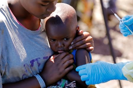 A child reacts as a health worker injects her with the Ebola vaccine, in Goma