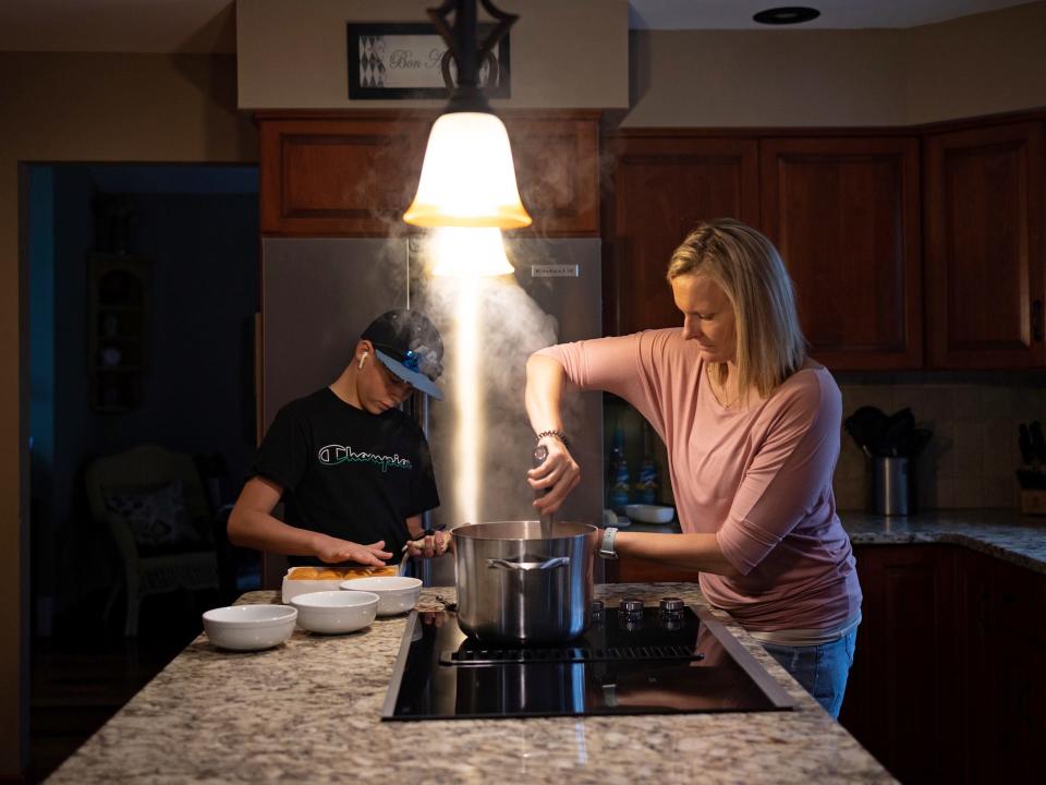 woman stirs pot on stove under light fixtures