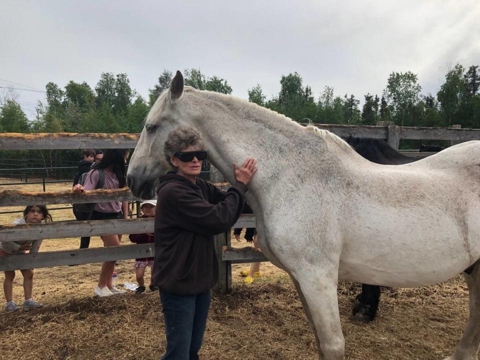 Patricia Dartnell, who runs North Country Stables, is shown here alongside Norman, the horse celebrating his retirement with Yellowknife's equestrian community.  (Luke Carroll/ CBC - image credit)