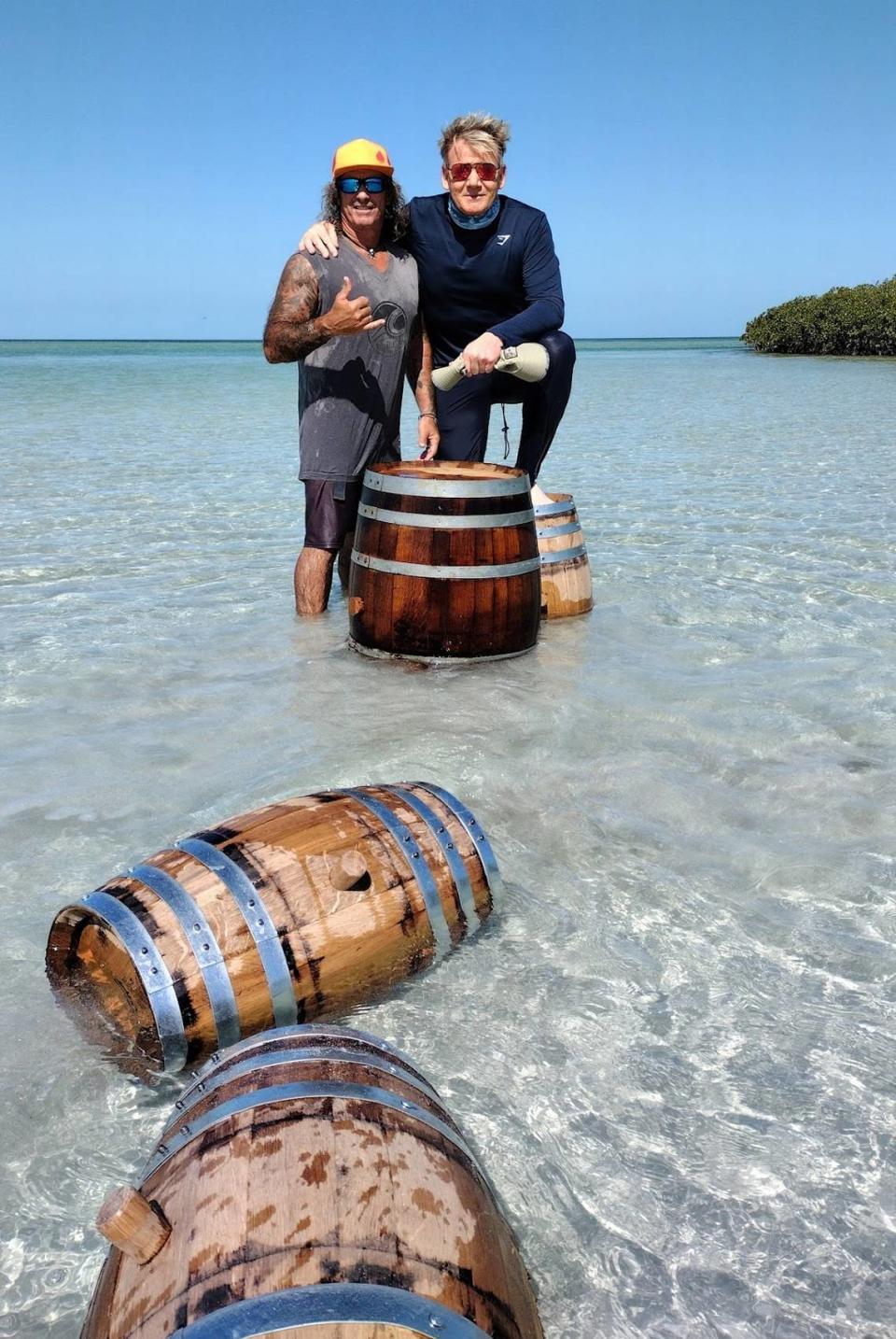 Restaurant owner and chef Paul Menta stands with celebrity chef Gordon Ramsay in the shallow Key West waters with oak barrels Menta uses to cure his rum.