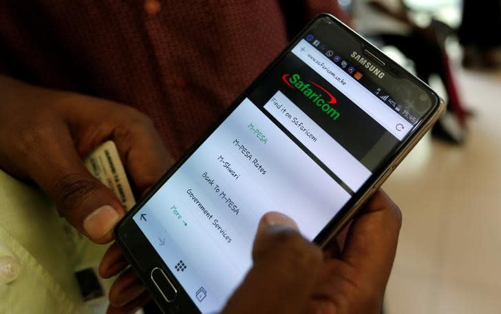 An employee assists a customer to set-up M-Pesa money transfer service on his handset inside a mobile phone care centre operated by Kenyan's telecom operator Safaricom; in the central business district of Kenya's capital Nairobi, May 11, 2016. REUTERS/Thomas Mukoya