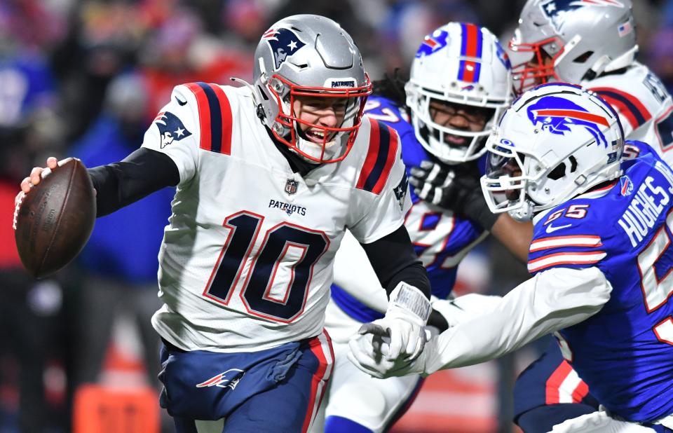 Patriots quarterback Mac Jones is forced to scramble by the Bills pass rush during the first quarter of the AFC wild-card playoff game on Saturday.