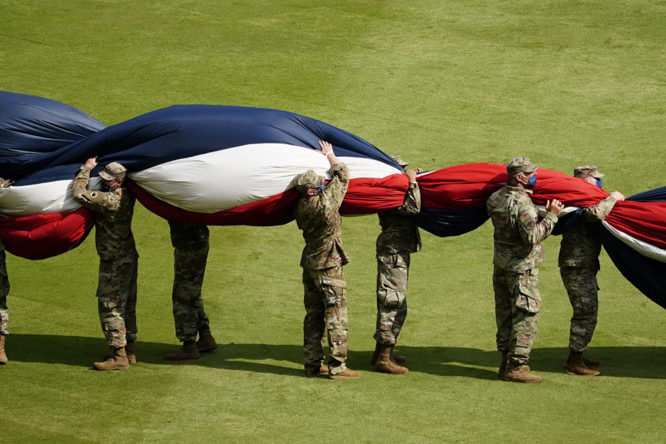 Military members work to gather up a large United States flag stretched across the outfield during a Memorial Day ceremony before a baseball game between the Washington Nationals and the Atlanta Braves, Monday, May 31, 2021, in Atlanta. (AP Photo/John Bazemore)