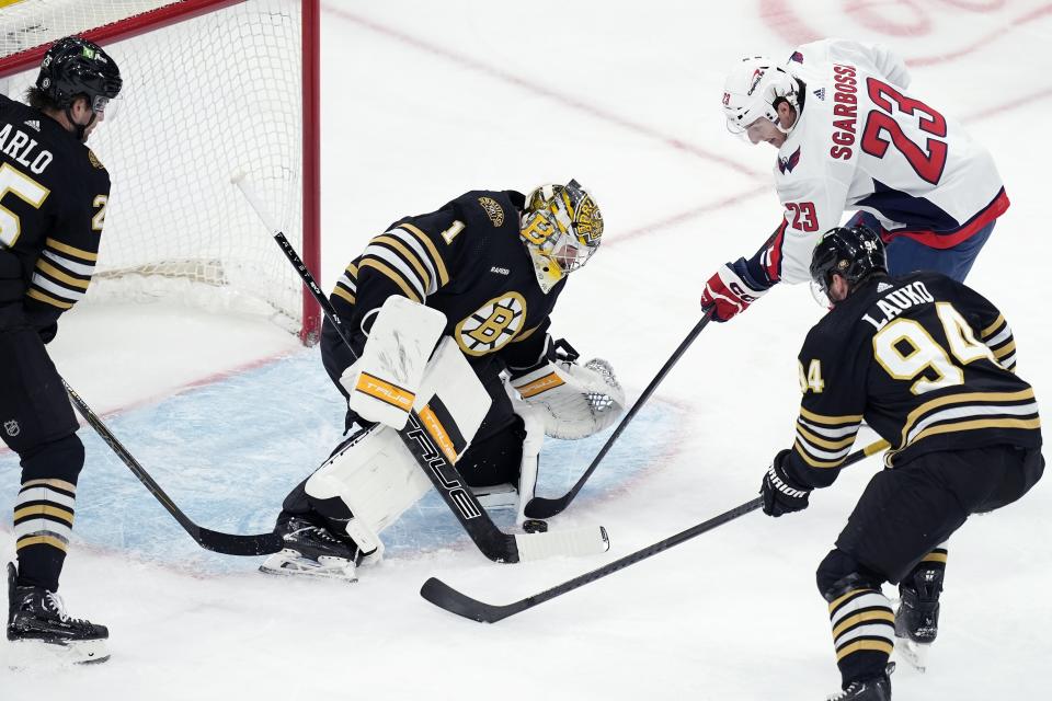 Boston Bruins' Jeremy Swayman (1) blocks a shot by Washington Capitals' Michael Sgarbossa (23) as Jakub Lauko (94) defends during the first period of an NHL hockey game, Saturday, Feb. 10, 2024, in Boston. (AP Photo/Michael Dwyer)